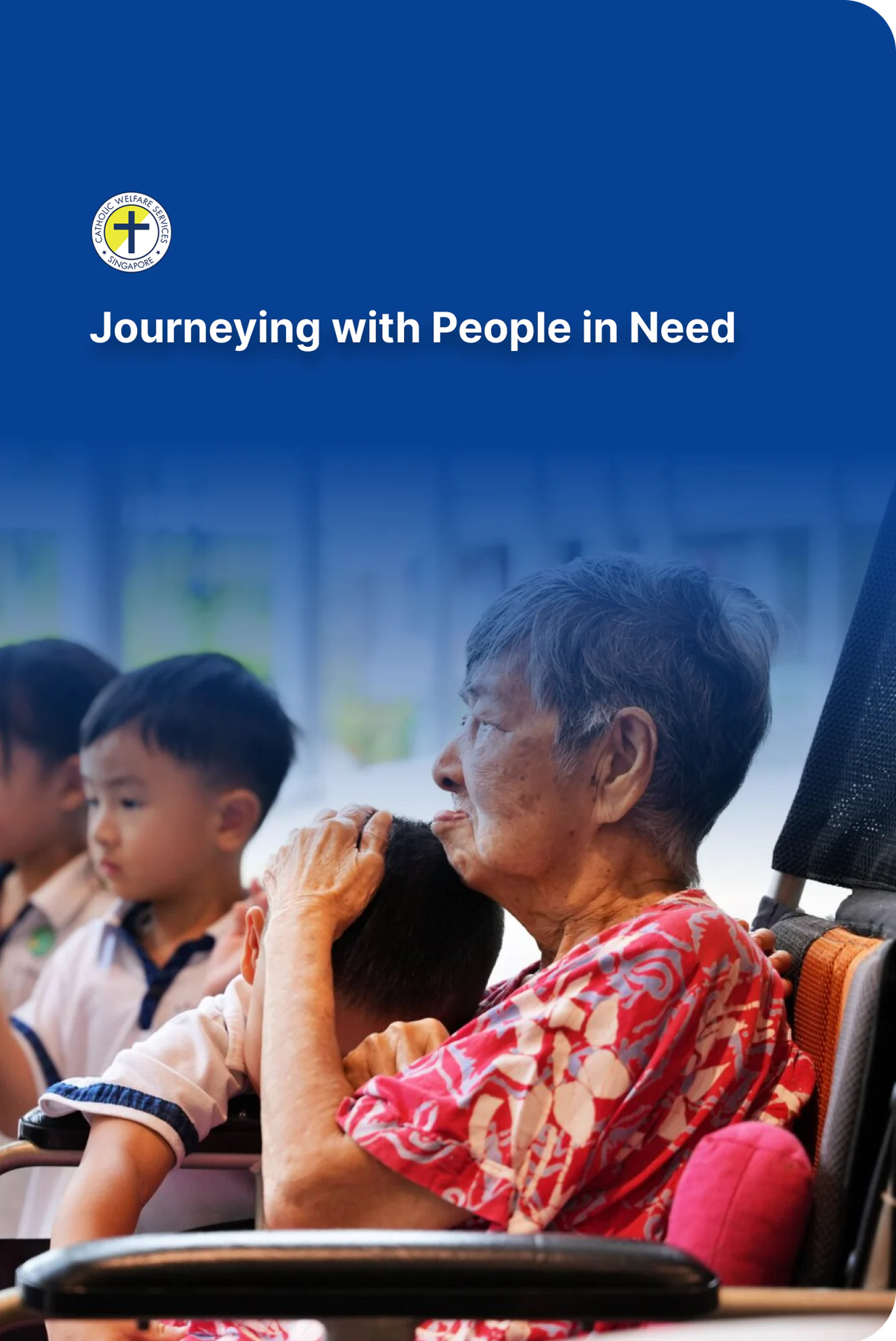 An older resident in a wheelchair holding a child close, under the Catholic Welfare Services crest and its line, Journeying with People in Need